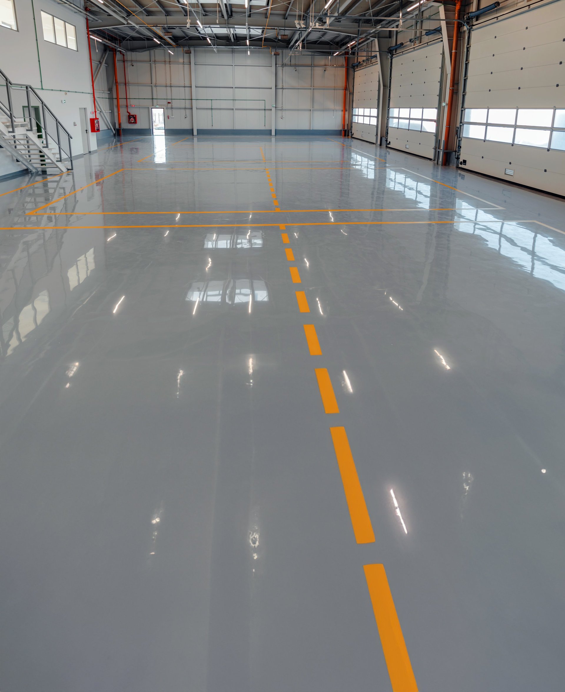 Large industrial space with glossy black and grey metallic epoxy swirl floor coating with reflective finish