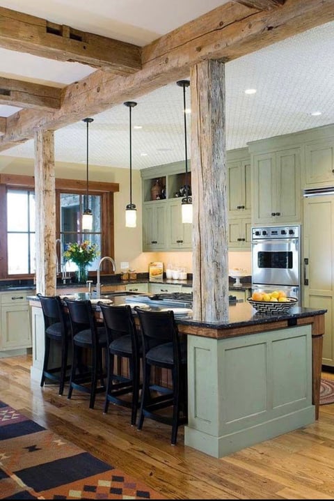 Farmhouse kitchen with sage green island, exposed wooden beams, stainless steel appliances