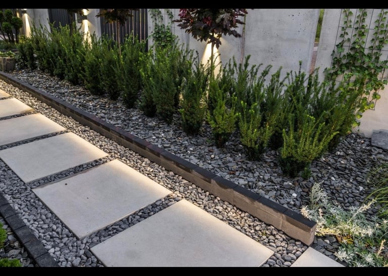 Modern pathway with concrete stepping stones and dark gravel bordered by green lavender plants and landscaping edging