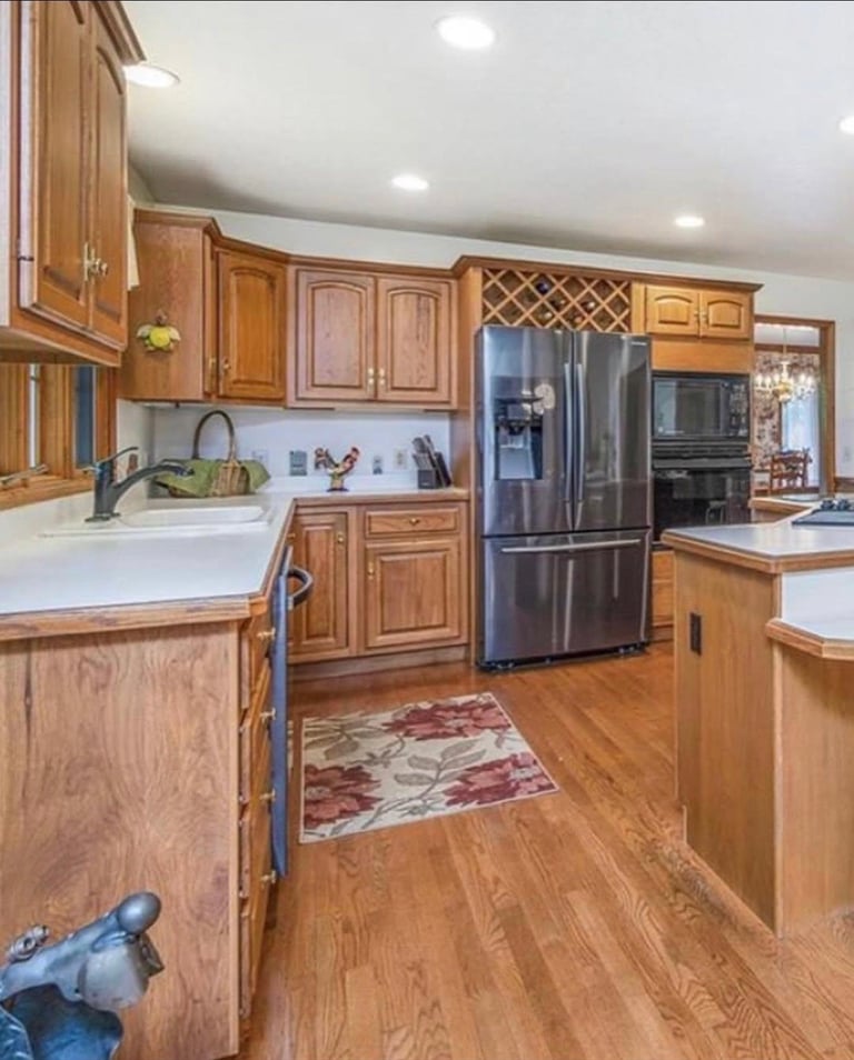 Modern kitchen with wood cabinetry, stainless steel appliances, white countertops, and hardwood flooring