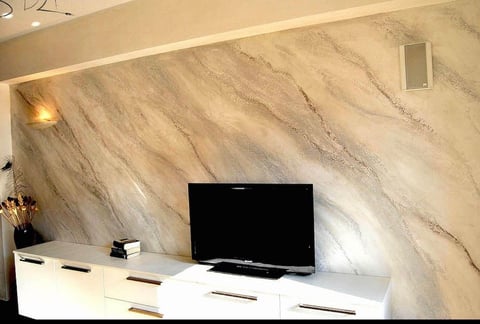 Modern living room with black flat-screen TV on white media console against marble-textured accent wall