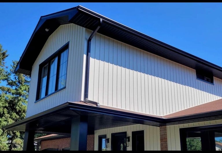 Modern two-story house with black metal frame, white corrugated metal siding, large windows, and open ground level under clear blue sky