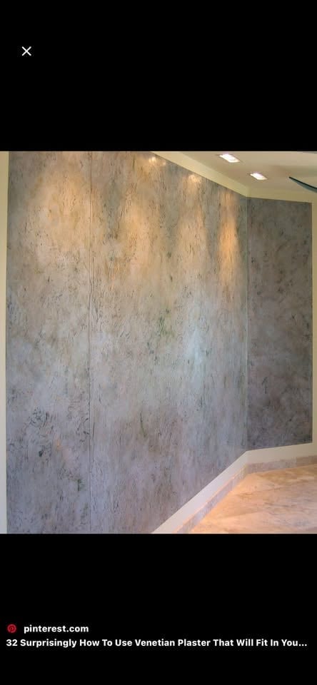 Modern room interior with textured Venetian plaster wall finish in warm grey and beige tones, recessed ceiling lights, and polished concrete floor