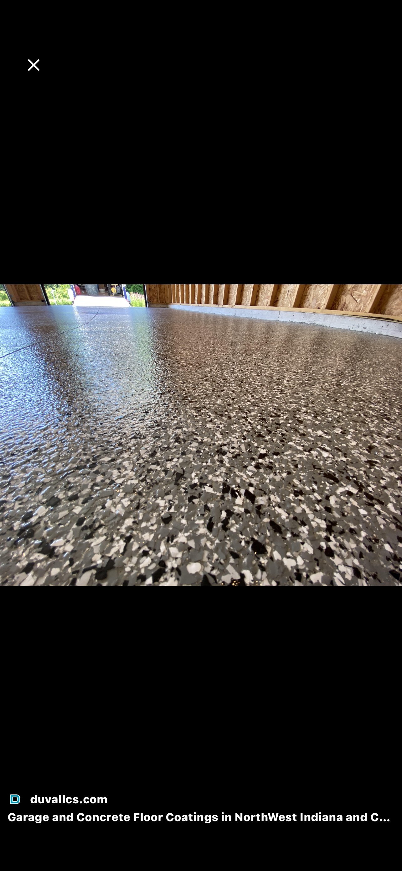 Low-angle view of a polished concrete floor with white speckled coating inside a garage with wooden framing visible