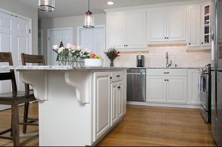 Modern white kitchen with stainless steel appliances, central island, and wooden flooring
