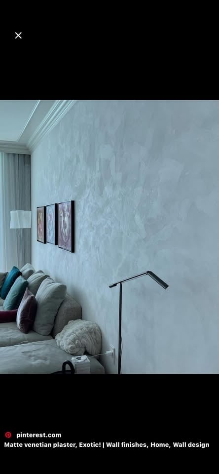 Modern bedroom with matte venetian plaster textured wall, bed with decorative pillows, framed artwork, and minimalist decor