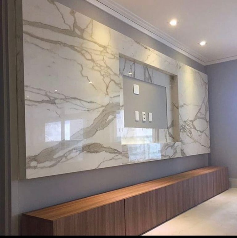 Modern interior wall with marble-patterned panels above a wooden media console with electrical outlets