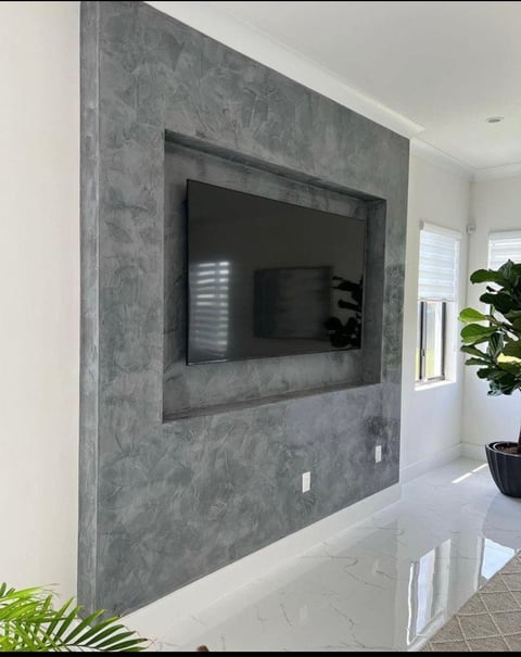 Modern living room with flat-screen TV mounted in a gray textured concrete wall accent