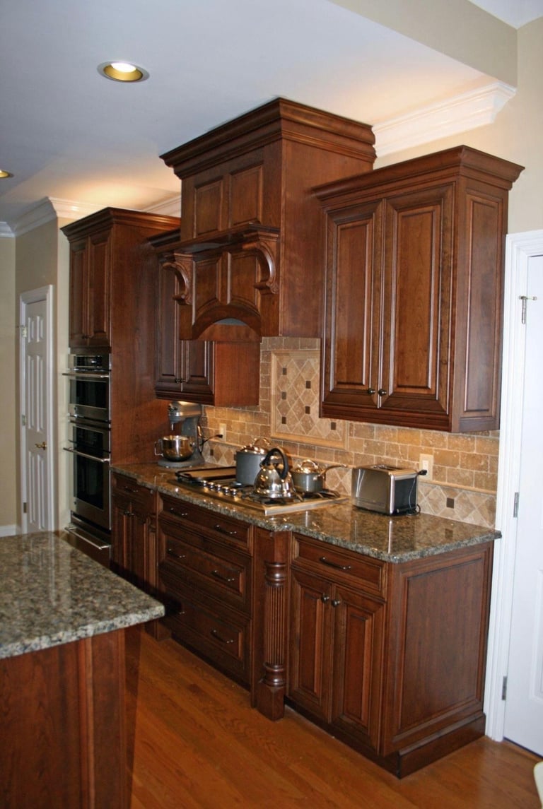 Upscale kitchen with dark wood cabinetry, granite countertops, tile backsplash, and stainless steel appliances