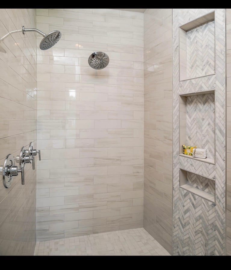Modern luxury bathroom shower with white subway tile walls, rainfall and handheld showerheads, glass enclosure, and built-in stone shelving