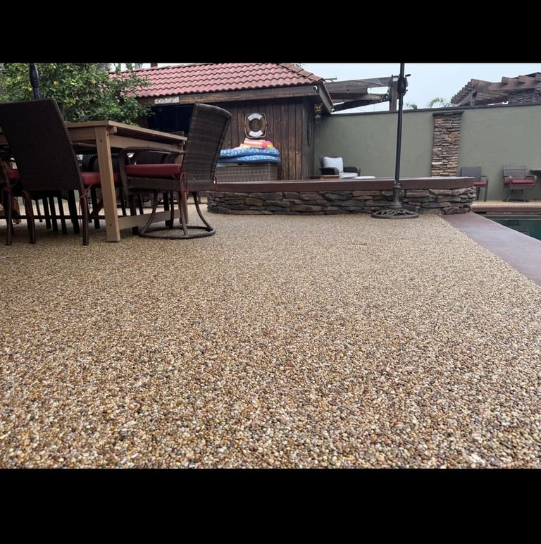 Backyard patio with gravel surface, wooden furniture, shed, and fenced enclosure on sunny day