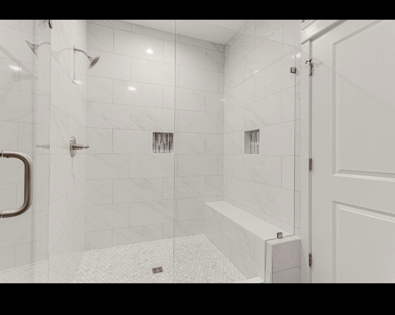 Modern luxurious bathroom with large walk-in shower, white subway tile walls, glass enclosure, rainfall showerhead, and white hexagonal floor tile